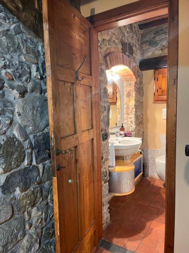 a bathroom with a stone wall and a wooden door at W il silenzio! in Gualdo