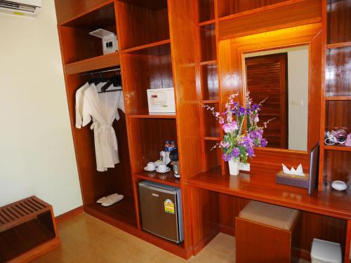 a room with a closet with a desk and flowers at The Sunset Beach Resort - Koh Kho Khao in Ko Kho Khao