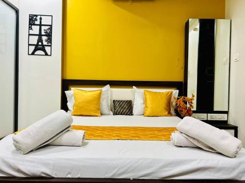 two beds in a room with yellow walls and yellow pillows at Palm Suite With Sky Terrace Penthouse 11th Floor in Rajkot
