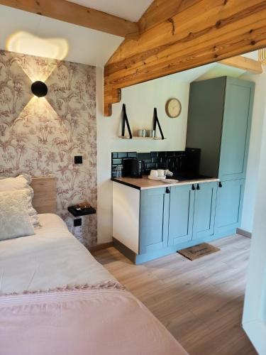 a bedroom with a bed and a kitchen with a counter at La cabane au bout du Thérain in Herchies