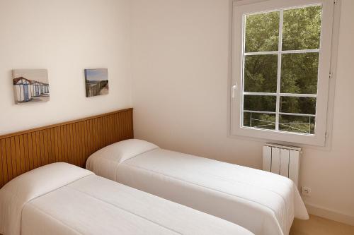 two beds in a room with a window at Serena Entre mer et forêt in Camiers