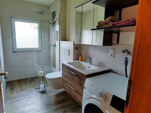 a bathroom with a sink and a washing machine at Landhaus Grimburg - Ferienwohnungen im Parterre und Obergeschoss in Grimburg