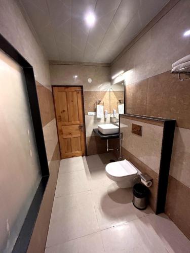 a bathroom with a toilet and a sink at Hidden Heaven Waterfall view in Manāli