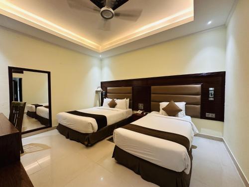 a hotel room with two beds and a mirror at Uni Resort in Cox's Bazar