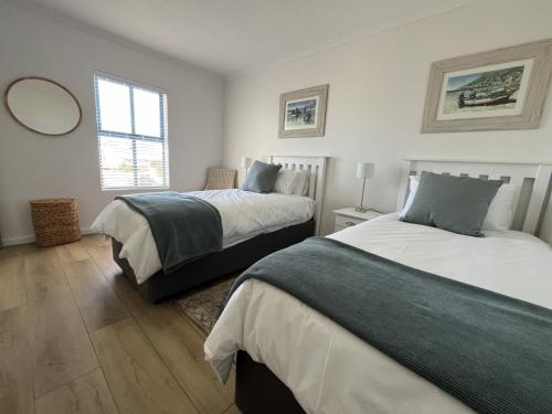 a bedroom with two beds and a mirror on the wall at Codrock Cottage in Langebaan