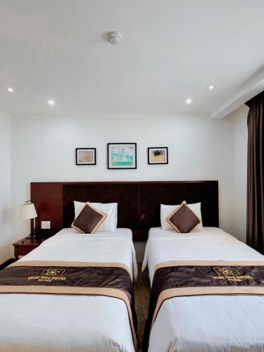 two beds in a hotel room with white walls at Ruby hotel Tuần Châu in Ha Long