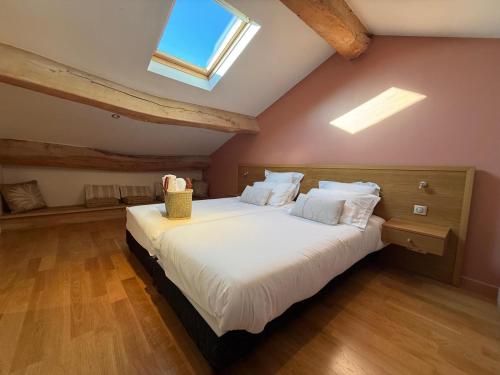ein Schlafzimmer mit einem großen weißen Bett und einem Dachfenster in der Unterkunft La ferme de Rapan Pérouges in Pérouges