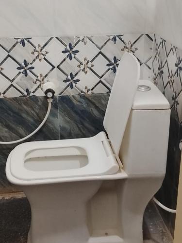 a white toilet with the seat up in a bathroom at Subhiksha Rooms in Bellūru