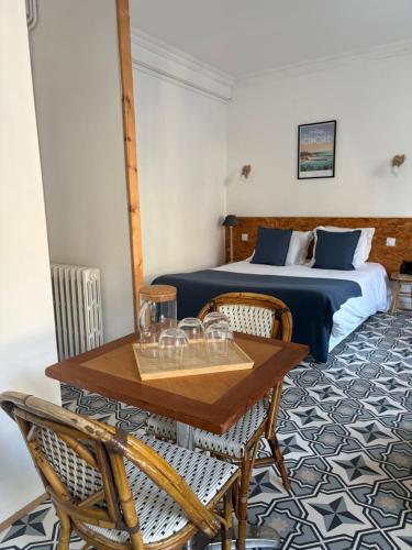 a bedroom with a bed and a table and chairs at Le Petit Café L'arriere Cour in Cancale
