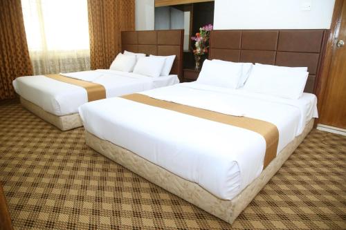 two beds in a hotel room with white beds at Holiday Xpress in Dhaka