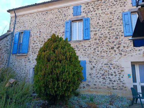 a building with blue windows and a bush in front of it at Hôtel Restaurant L'Orée du Vercors in Montmaur-en-Diois