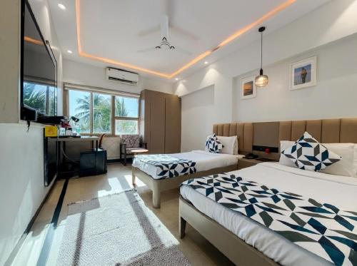 a bedroom with two beds and a desk and a television at asar Elite by Orion Hotels in Mumbai