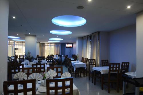 a dining room with tables and chairs and blue lights at Holiday Xpress in Dhaka