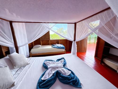 a bedroom with a white bed with a robe on it at Luz Amazônia Lodge in Aiparuça