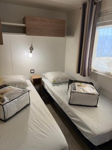 two twin beds in a room with a window at Mobil home 459 in Pont-Aven