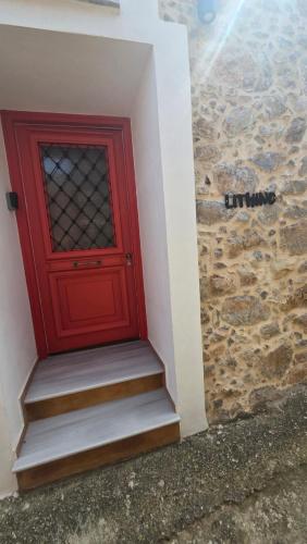a red door with stairs next to a stone wall at Lithino in Líthion