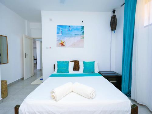 a bedroom with a large white bed with blue accents at Chui de eagle in Mombasa