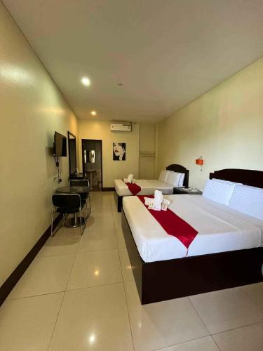 a hotel room with two beds and a desk at Hollywood Suites Gensan in General Santos