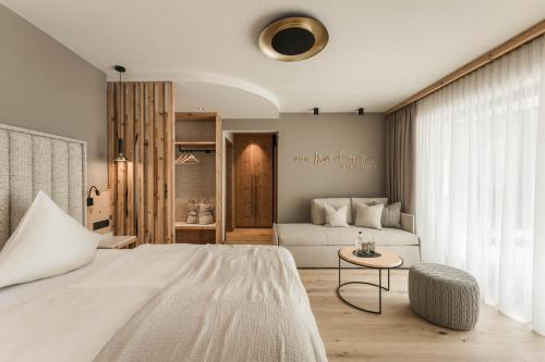 ein Schlafzimmer mit einem großen weißen Bett und einem Tisch in der Unterkunft Forster's Naturresort in Neustift im Stubaital
