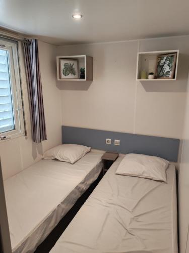 two beds in a small room with a window at Mobil home - 8 couchages avec lit bébé - ECRIN DE SÉRÉNITÉ - Camping TIKAYAN 5 étoiles - Le Muy in Le Muy