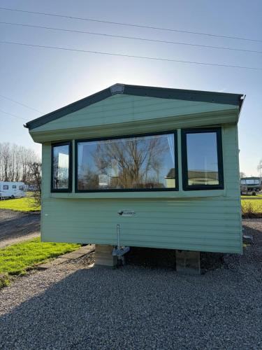 a green tiny house sitting on top of gravel at Chequers Inn in Harrogate