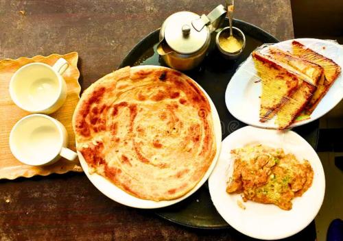 a table with two plates of food and a pie at Golden One Hotel in Lahore