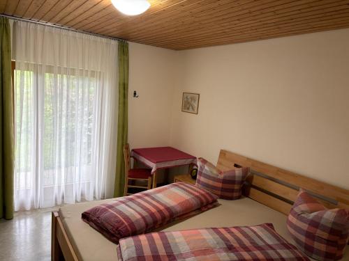 a bedroom with two beds and a table and a window at Breighof in Biberach bei Offenburg