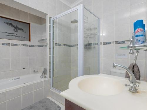 a bathroom with a shower and a tub and a sink at Haweweg 5 in Struisbaai