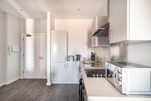 a kitchen with white cabinets and a white refrigerator at Modern & Spacious 2 Bed Apartment in Waterloo Liverpool in Waterloo