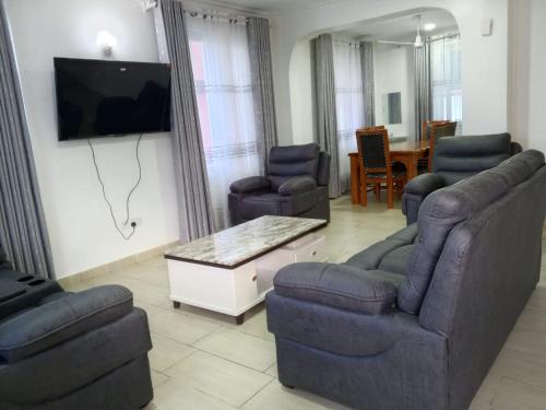 a living room with a couch and chairs and a tv at Greenwood Apartments in Mtwapa