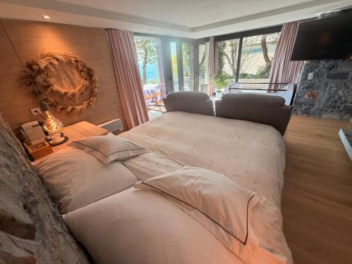 a bedroom with a large bed with a large window at ROMANTIC SUlTE WITH ITS OWN SPA AND OPEN VIEW TO LUGANO in Cademario