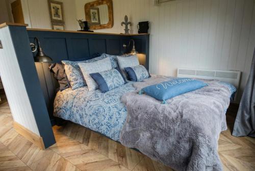 a bedroom with a blue bed with blue pillows at Secluded Countryside Shepherd's Hut on Working Farm near Audley in Audley