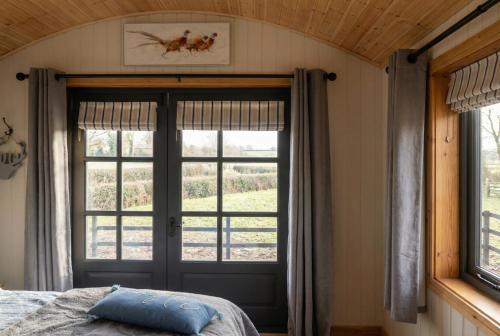 a bedroom with a bed and a large window at Secluded Countryside Shepherd's Hut on Working Farm near Audley in Audley