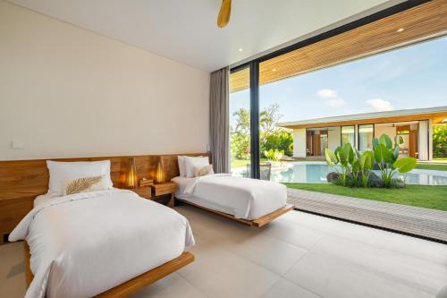 two beds in a bedroom with a large window at Uluwatu Zen Villas in Badung