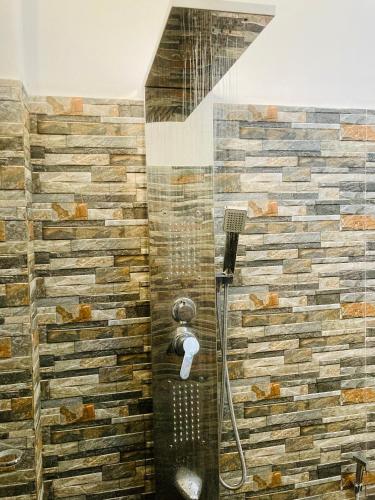 a shower in a bathroom with a stone wall at The Aurelian in Ella