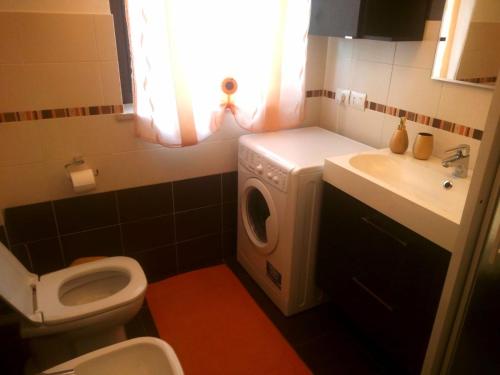 a bathroom with a toilet and a sink and a washing machine at Casa Cesano mare in Senigallia