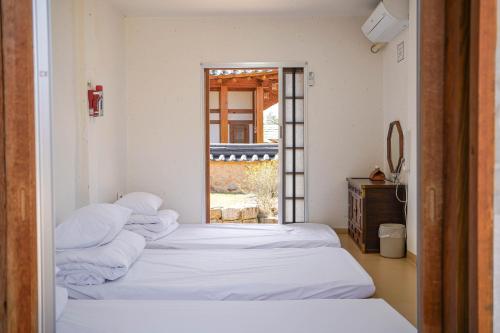 a room with two beds with white sheets and a window at 청송 한옥호텔 안 in Imjŏn-dong
