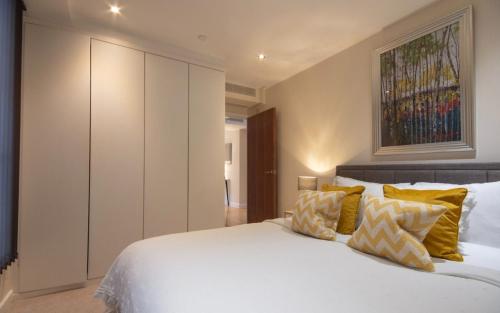 a bedroom with a large white bed with yellow pillows at Westminster 1 bed apt with terrace and Air-Con in London