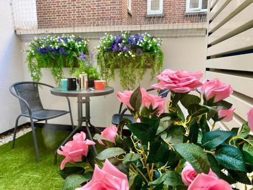 a patio with pink roses and a table and flowers at Westminster 1 bed apt with terrace and Air-Con in London