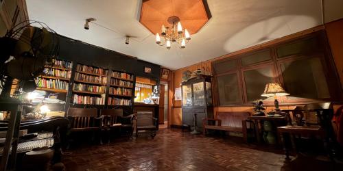 a library with chairs and bookshelves and a chandelier at Villa Guesthouse Bangkok in Bangkok