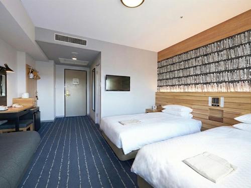 a hotel room with two beds and a desk at Hearton Hotel Nishi Umeda in Osaka