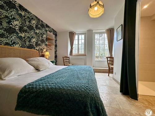 a bedroom with a large bed with a blue blanket at Le Bief in Pont-et-Massène
