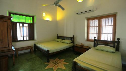 two beds in a room with two windows at Monsoon Villa in Puttalam