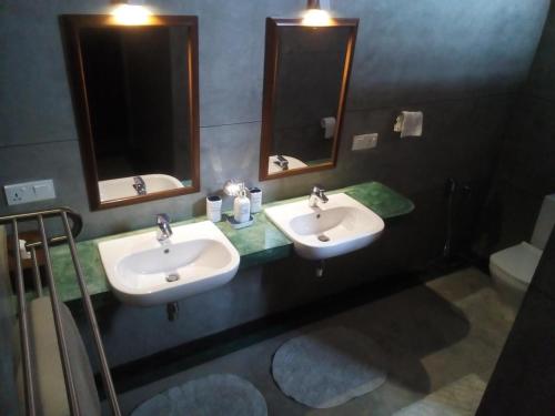 a bathroom with two sinks and two mirrors at Monsoon Villa in Puttalam