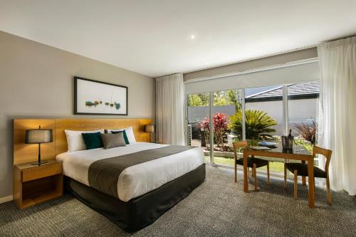 a hotel room with a bed and a desk and a window at Quest Brighton on the Bay in Melbourne