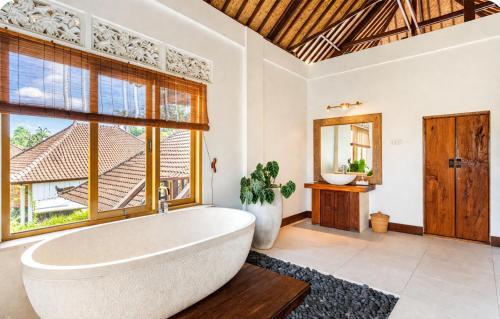 a bathroom with a large tub and a window at Villa Kami Ubud in Ubud