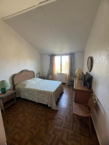 a bedroom with a bed and a table and a window at maison 50m plage in Belvédère-Campomoro