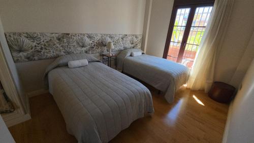 a bedroom with two beds and a window and a window at CasaManuelaMonesterio in Monesterio
