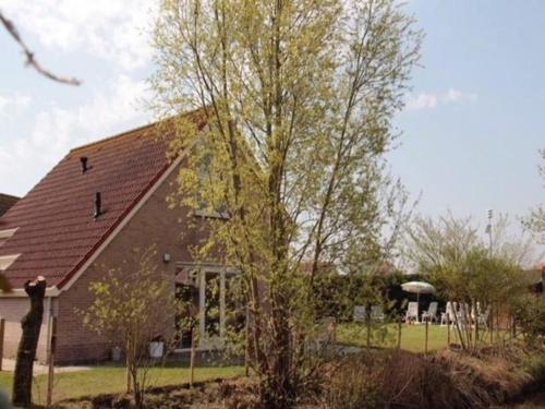 a house with a tree in front of it at Appealing bungalow with garden in Breskens