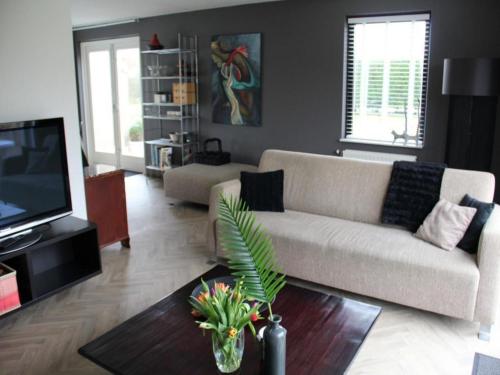 a living room with a couch and a tv at Appealing bungalow with garden in Breskens